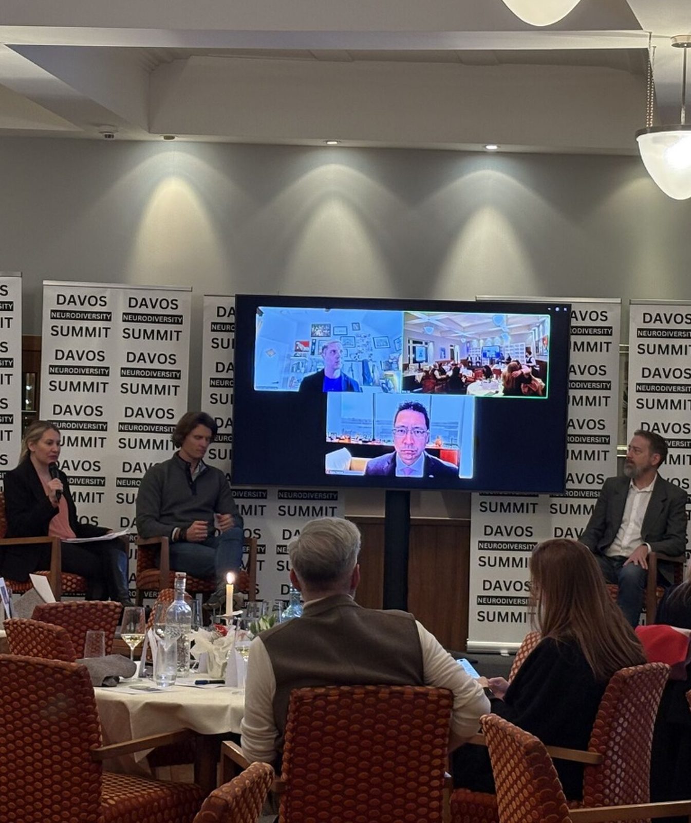 Panel discussion at DNS 2026, four speakers on stage with a hybrid video call displayed on screen behind them