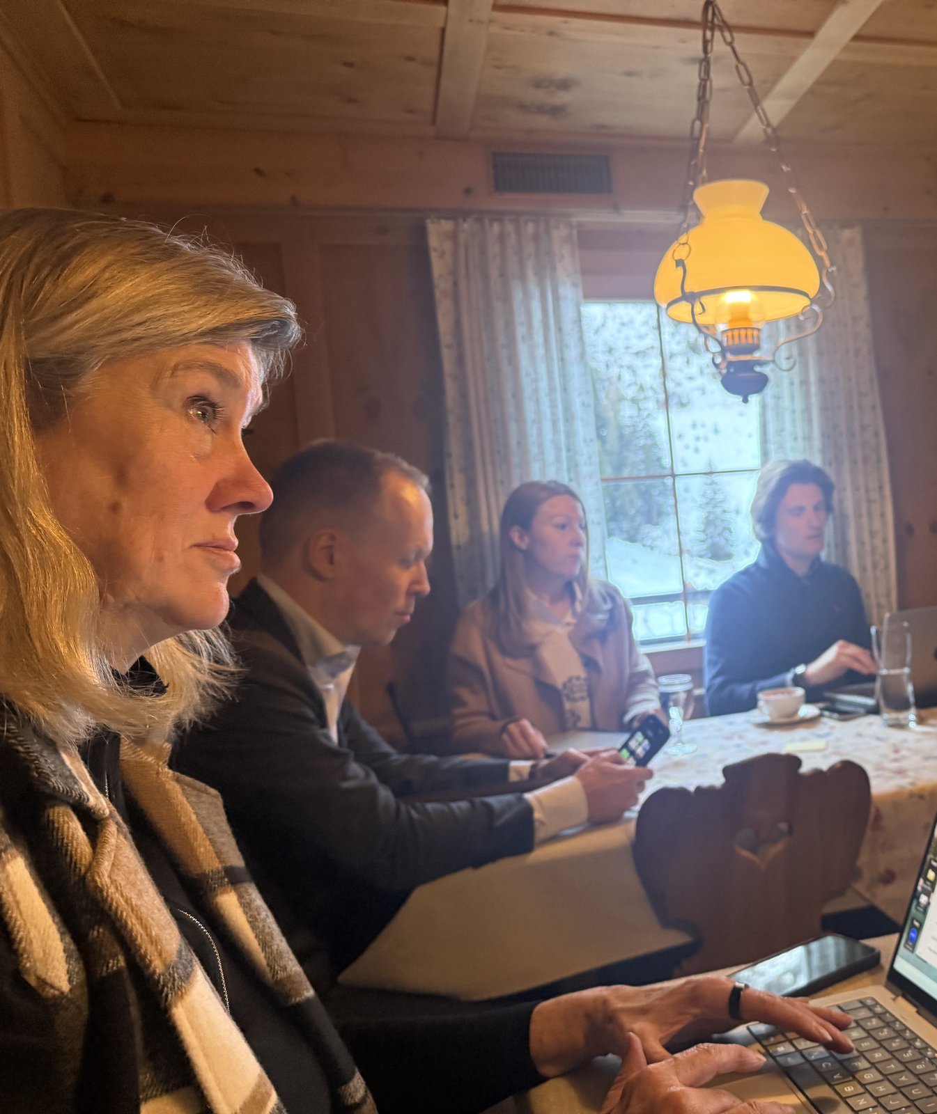 Maureen and attendees in discussion inside the Alps chalet workshop, snow visible through the window